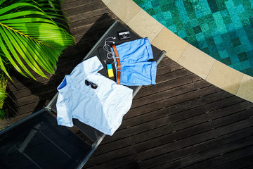 Man summer clothes collage flat lay isolated on dark wood background with swimming pool. Summer...