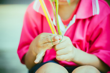 Close-up to kindergarten hands are tied with rubber for to make merit and candle light on Makha Bucha Day