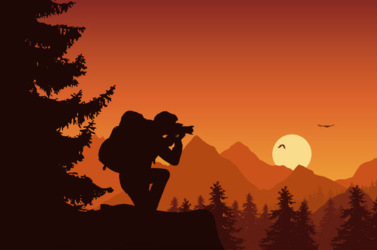 Mountain landscape with forest and tourist photographing flying birds on an orange sky