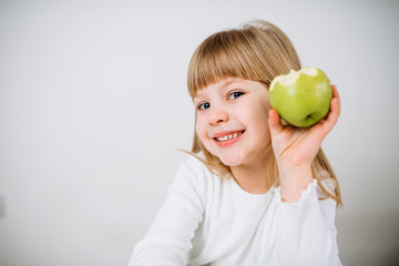 Fototapeta premium Portrait of a beautiful little girl holding green apple.