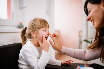 Little girl and mother applying face creme. Skincare concept.