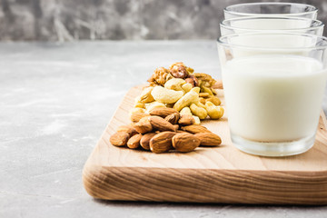 Vanilla nut milk in glasses on wooden board on concrete background. Selective focus, copy space. 