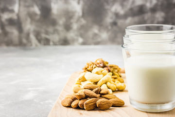 Homemade nut milk in glasses on wooden board on concrete background. Selective focus, copy space. 