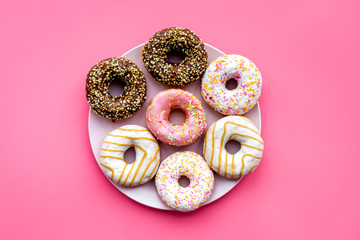 Sweet tasty snack. Glazed donut on plate on pink background top view copy space