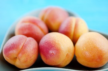 Peaches delicious fruit in a heart shaped plate on a blue wooden background
