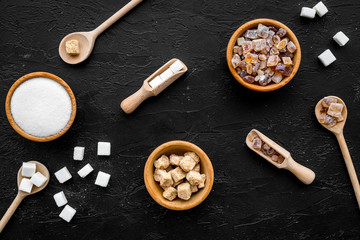 Sugar background on black. Bowls with different kinds of sugar. Top view