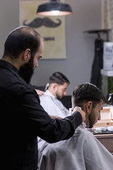 Obraz premium Hairdresser cutting hair to a client with an electric machine