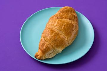 Croissant on violet background. 