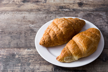 Croissant in plate on wooden table. Copyspace
