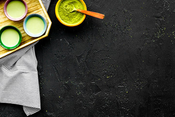 Japanise tea ceremony with matcha tea. Bowl with powder and cups with beverage on tablecloth black background top view copy space
