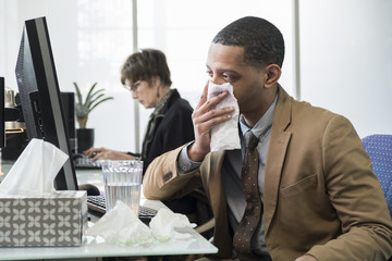Business man coughing and sneezing in a small office