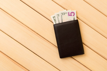 Leather wallet with dollars on wooden table background