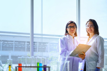 Young female scientist standing with techer in lab worker making medical research in modern...
