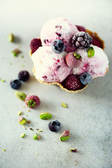 Pink ice cream with berries, strawberries, blueberries, raspberries, pistachios in waffle basket. Summer food concept, copy space. Healthy gluten free fruit ice-cream. Banner