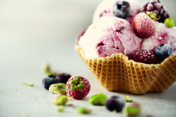 Pink ice cream with berries, strawberries, blueberries, raspberries, pistachios in waffle basket. Summer food concept, copy space. Healthy gluten free fruit ice-cream. Banner