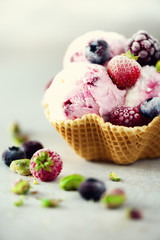 Pink ice cream with berries, strawberries, blueberries, raspberries, pistachios in waffle basket. Summer food concept, copy space. Healthy gluten free fruit ice-cream. Banner