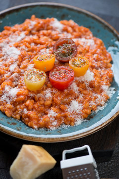 Tomato risotto topped with fresh sliced mini tomatoes and grated parmesan, selective focus, close-up