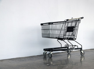 Black shopping Cart on the floor and white background. trolley is a cart supplied by a shop, especially supermarkets, for use by customers for transport  to checkout counter during shopping. © Achisatha