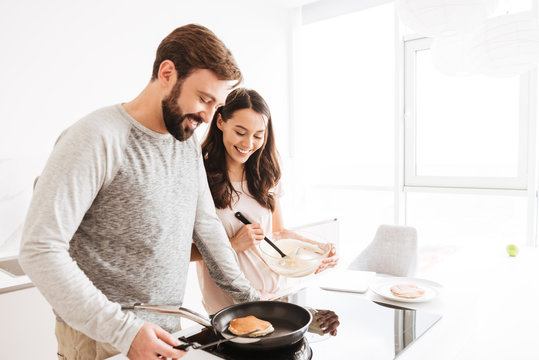 Portrait of a smiling young couple cooking pancakes