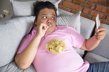 lazy male having meal while using mobile phone