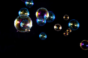 Abstract rainbow color soap bubbles floating in the dark.