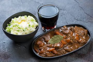 Irish beer and beef stew with champ mash and dark beer on a grey asphalt background, studio shot