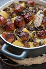 Closeup of a baking form with Dublin coddle or Irish dish of sausages, bacon, onions and potatoes, vertical shot
