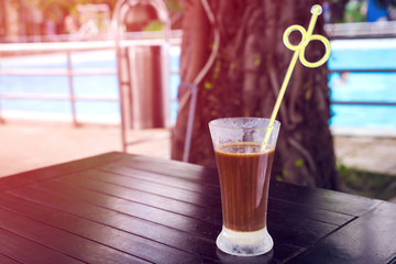 traditional Vietnamese coffee with condensed milk in a tall glass near the swimming pool