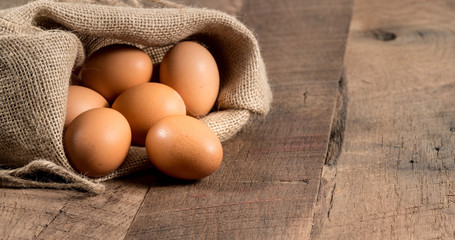 Freshly laid organic eggs in burlap sack on wood