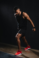 Fototapeta na wymiar full length view of muscular young african american man in sportswear exercising on black