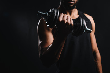 Fototapeta na wymiar cropped shot of muscular african american man exercising with dumbbell isolated on black