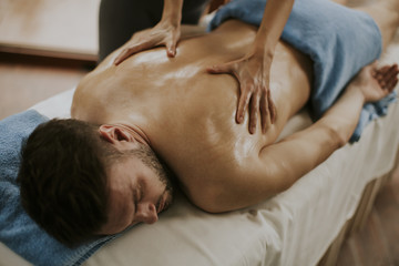 Obraz na płótnie Canvas Young man having massage in the spa