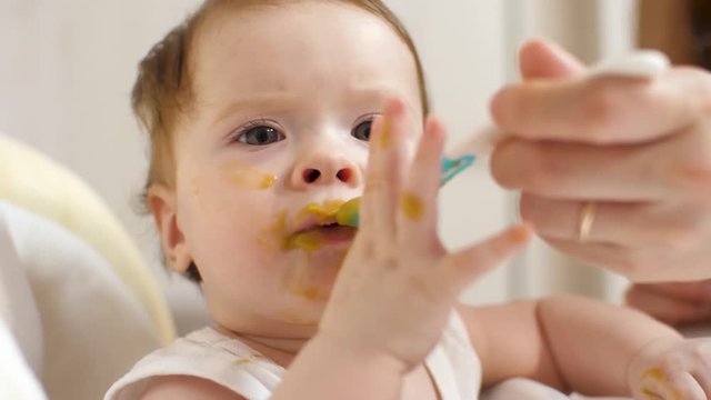mom feeds toddlers breakfast from baby spoon with delicious puree for children