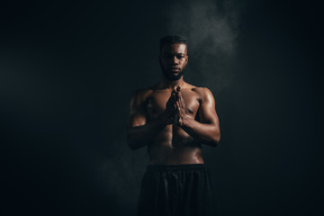 young african american sportsman applying talcum powder and looking at camera on black