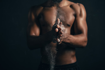 cropped shot of african american sportsman applying talcum powder on hands on black
