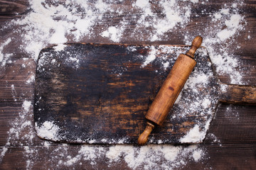Rolling pin and flour on black table. Copy space. Top view