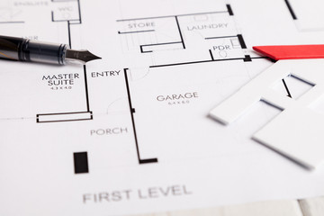 Small house with calculator over technical drawing of a house.