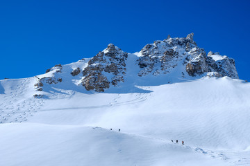 Fototapeta na wymiar Paraglider starts in winter mountain landscape, shot against the sun, blue sky, horizontal