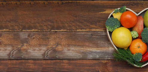 Fruits and Vegetables in Heart shaped Wooden Box. Broccoli, apples, Pepper, tangerine over Wooden Background. Banner. Health food Concept with copy space.