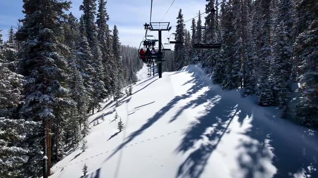 Ski lift through snow covered evergreen trees on a sunny day