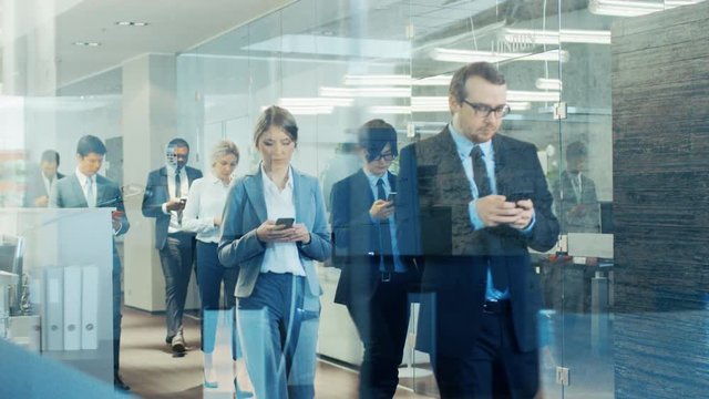 Through the Glass Shot of  Business People Marching Through the Corporate Building Hallway. Multicultural Crowd Of Focused Businessmen and Businesswomen Coming To Work, Entering Offices. 
