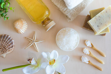 Top view of Wellness setting. Sea salt, soap, towel, olive oil and flowers on wooden background