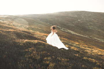 Beautiful bride with a bouquet on mountain background at sunset