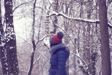 Fototapeta na wymiar woman head with wool bobble hat in a forest while snowing