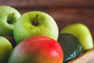 Wet fresh green fruit and vegetables in a wooden box in a kitchen. The concept of organic and healthy food.