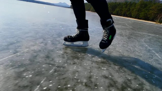 Legs of unrecognizable sportsman in ice skates. Man stay on frozen lake  in sunny winter nature