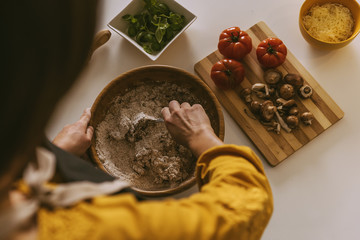 Woman preparing delicious pizza with healthy ingredients.