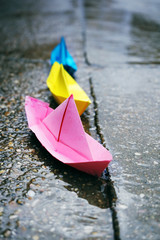 Barco de papel de colores sobre un charco de lluvia 