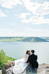 Wedding couple at breathtaking landscape with rock and lake.