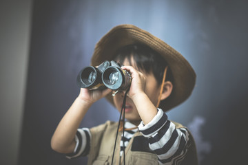 A adventure boy is preparing a camera and a binocular.